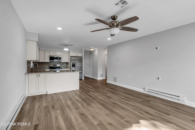 kitchen featuring visible vents, a sink, a baseboard heating unit, and stainless steel appliances