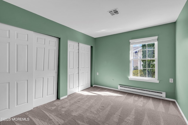 unfurnished bedroom featuring baseboards, a baseboard heating unit, and carpet