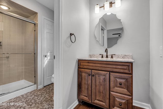bathroom featuring vanity, toilet, baseboards, tile patterned floors, and a shower stall