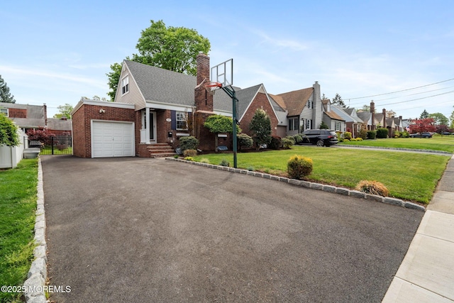 view of front of property featuring a front yard, a garage, brick siding, fence, and aphalt driveway
