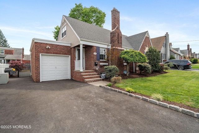 view of front of property featuring aphalt driveway, a front yard, a chimney, brick siding, and an attached garage