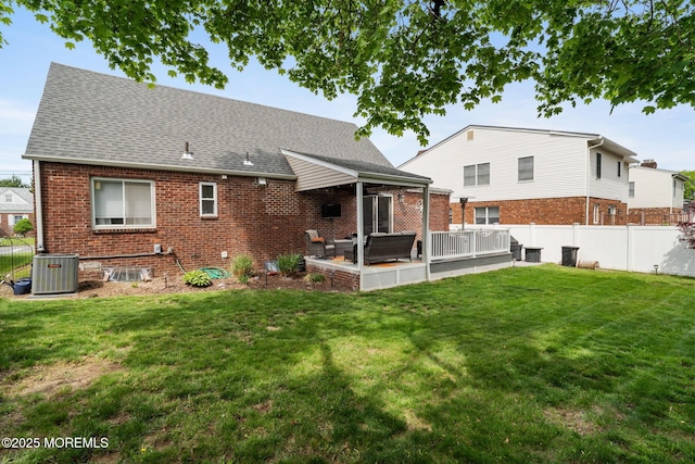 rear view of property featuring a lawn, central AC, and a fenced backyard