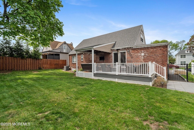 back of property featuring fence, a yard, a deck, and brick siding