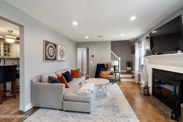 living room with recessed lighting, visible vents, wood finished floors, and stairway