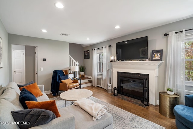 living area with visible vents, a fireplace with flush hearth, wood finished floors, stairway, and recessed lighting