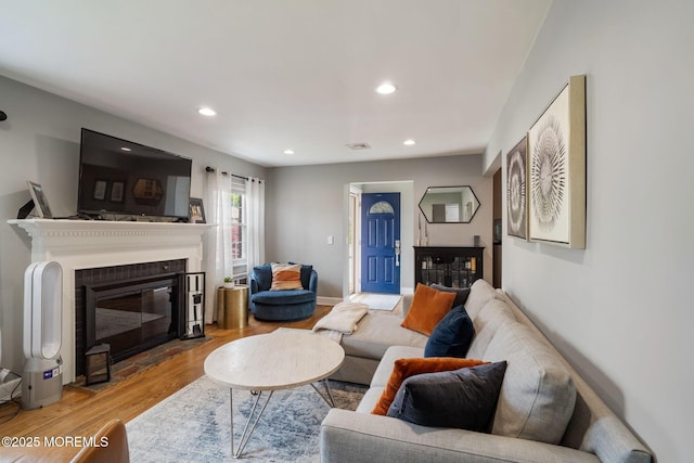 living room featuring recessed lighting, a fireplace with flush hearth, and wood finished floors