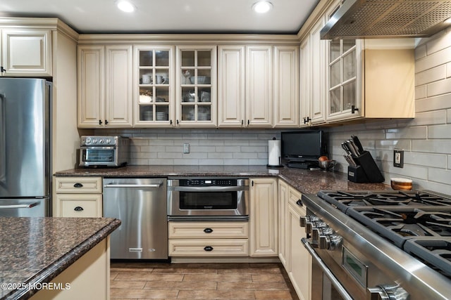 kitchen featuring wall chimney exhaust hood, appliances with stainless steel finishes, and cream cabinets
