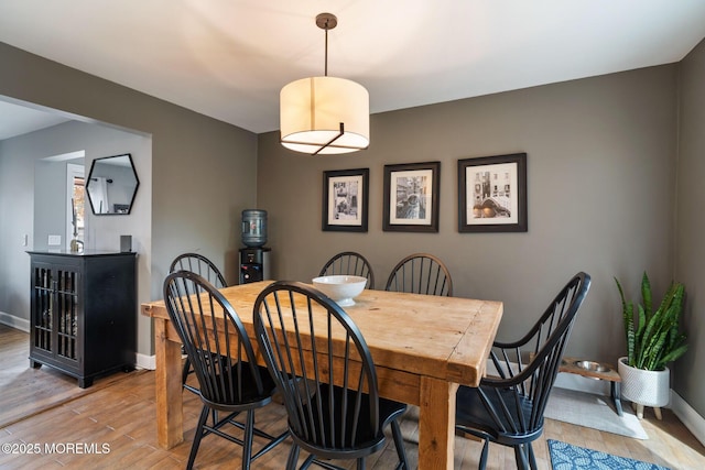 dining area featuring baseboards and light wood-type flooring