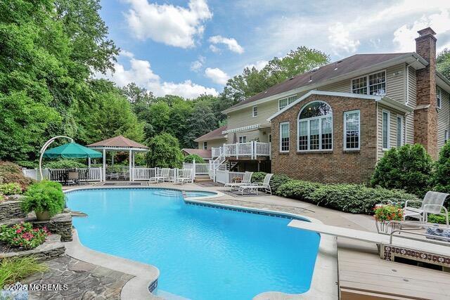 65 Devonshire Dr, Morganville, NJ 07751 - view of pool featuring a diving board, a wooden deck, a patio area, fence, and a fenced in pool