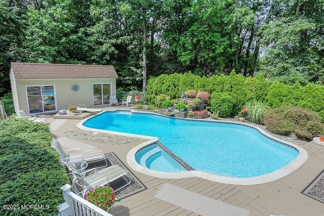 65 Devonshire Dr, Morganville, NJ 07751 - view of pool featuring a diving board, a pool with connected hot tub, a wooden deck, an outdoor structure, and an exterior structure