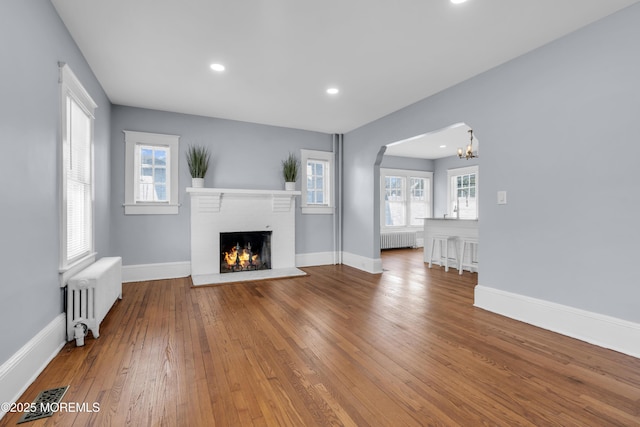 191 State Route 35, Red Bank, NJ 07701 - unfurnished living room featuring radiator heating unit, arched walkways, wood-type flooring, and a fireplace