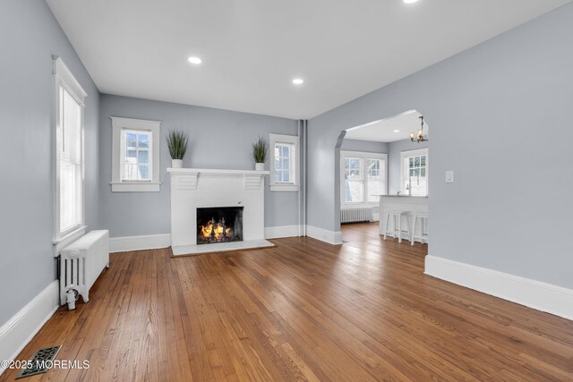 191 State Route 35, Red Bank, NJ 07701 - unfurnished living room featuring radiator heating unit, arched walkways, wood-type flooring, and a fireplace