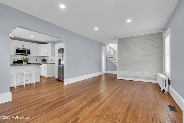 191 State Route 35, Red Bank, NJ 07701 - unfurnished living room featuring visible vents, radiator, stairs, light wood-type flooring, and arched walkways