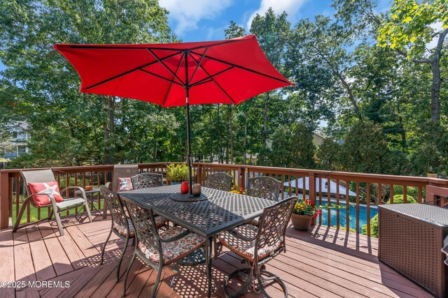 deck with outdoor dining space and an outdoor pool