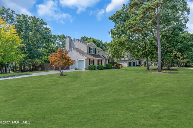new england style home featuring driveway, a chimney, a front yard, and a garage