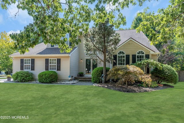 view of front of home featuring roof with shingles and a front yard