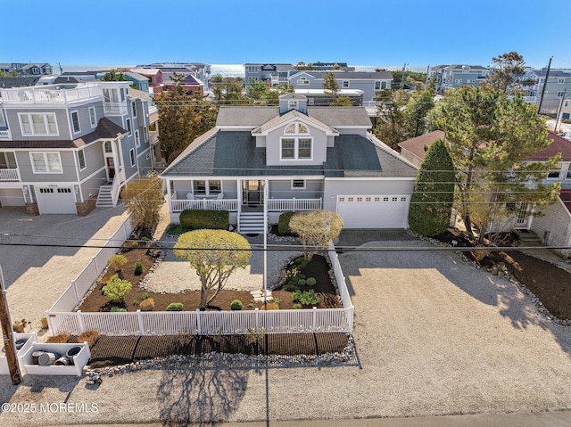 view of front facade featuring a fenced backyard, dirt driveway, covered porch, and a garage