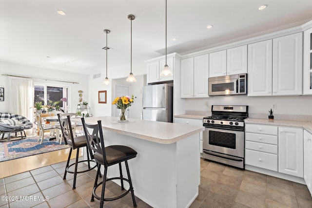 kitchen with light countertops, a center island, stainless steel appliances, and white cabinetry