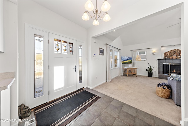 foyer entrance featuring carpet flooring, baseboards, a chandelier, and lofted ceiling