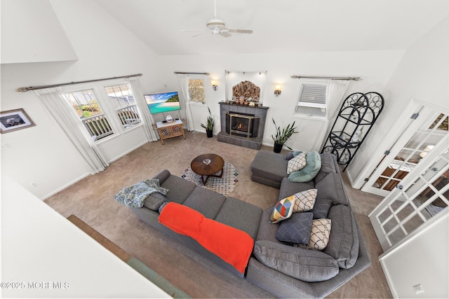 carpeted living area with baseboards, ceiling fan, and a tile fireplace