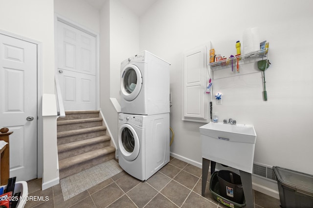 clothes washing area with dark tile patterned flooring, baseboards, visible vents, and stacked washer / dryer