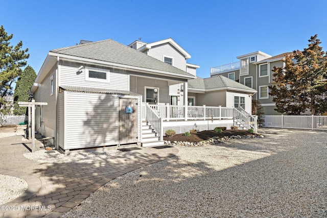 rear view of property featuring covered porch, fence, and stairs