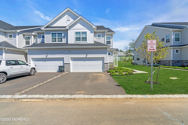 view of property with stone siding, a garage, aphalt driveway, board and batten siding, and a front yard