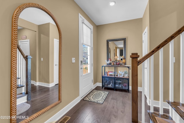 foyer featuring visible vents, arched walkways, wood finished floors, baseboards, and stairs