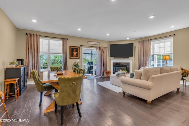 dining space with recessed lighting, dark wood-style flooring, a healthy amount of sunlight, and a fireplace