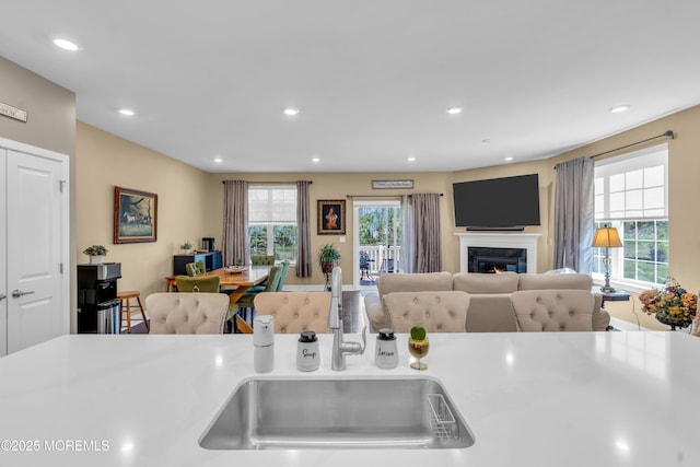 kitchen with recessed lighting, open floor plan, a glass covered fireplace, and a sink