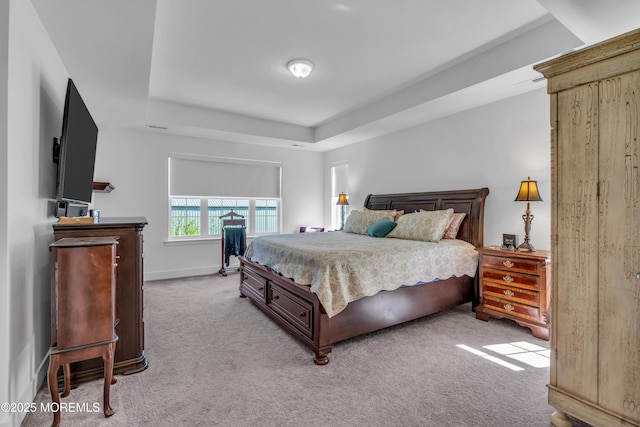 bedroom featuring baseboards, light colored carpet, and a raised ceiling