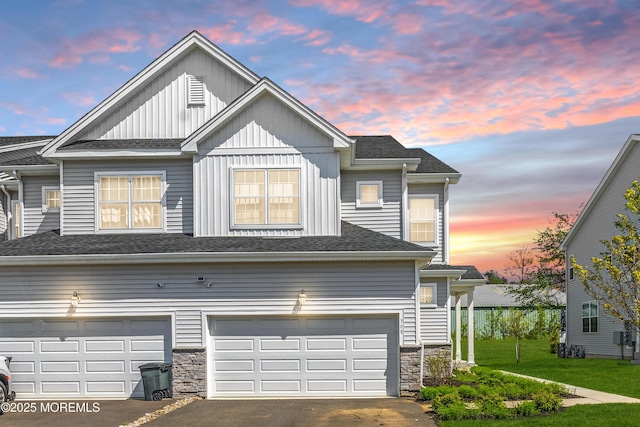 view of front of house with a garage, aphalt driveway, stone siding, roof with shingles, and board and batten siding