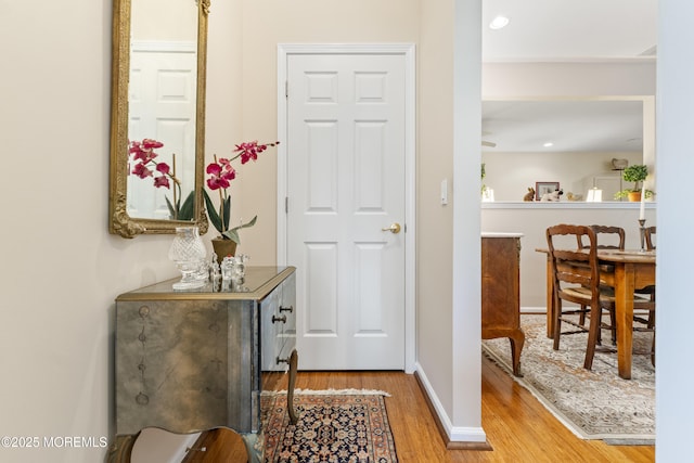 hallway featuring wood finished floors, baseboards, and recessed lighting
