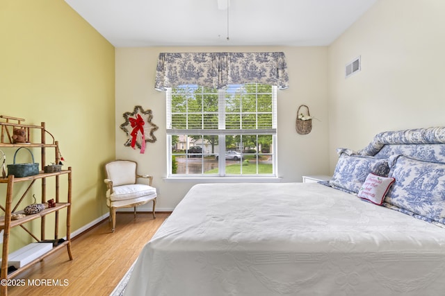 bedroom featuring visible vents, wood finished floors, baseboards, and ceiling fan