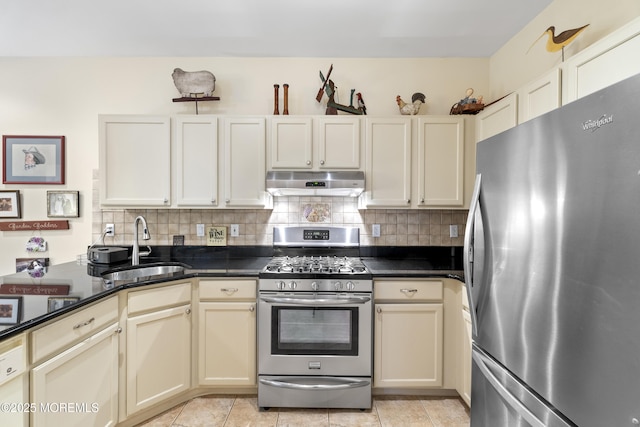 kitchen featuring under cabinet range hood, a sink, cream cabinetry, decorative backsplash, and stainless steel appliances