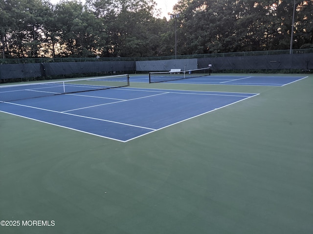 view of tennis court featuring fence and community basketball court