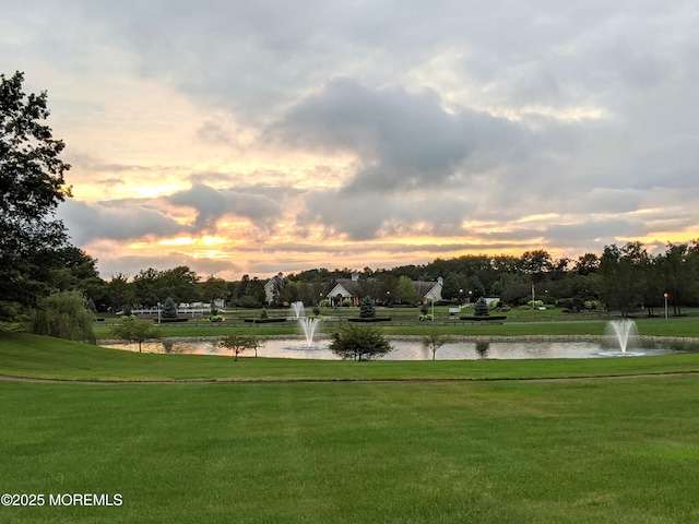 surrounding community with a water view and a lawn