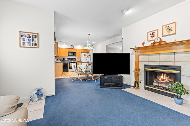 living room featuring baseboards, light colored carpet, light tile patterned floors, and a tile fireplace
