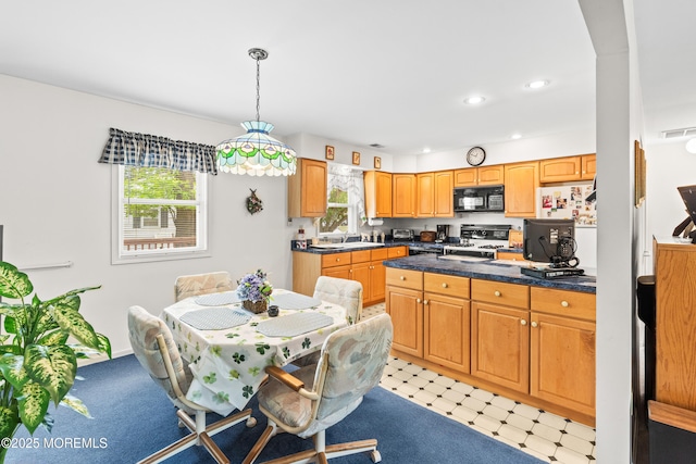 kitchen featuring visible vents, black microwave, dark countertops, range, and a sink