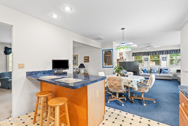 kitchen with a peninsula, open floor plan, dark countertops, and a kitchen bar
