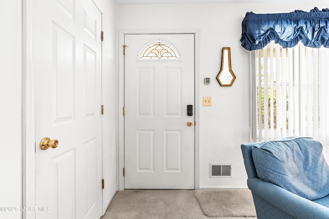 foyer featuring light colored carpet, baseboards, and visible vents