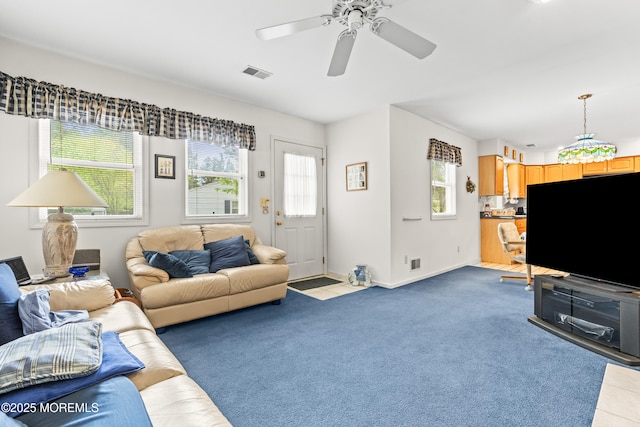 living room with ceiling fan, visible vents, light carpet, and baseboards
