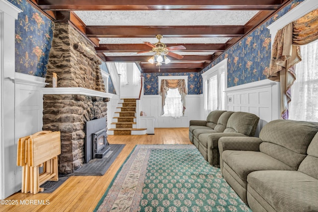 125 W Main St, Freehold, NJ 07728 - living area with ceiling fan, a wood stove, a wainscoted wall, wallpapered walls, and hardwood / wood-style flooring