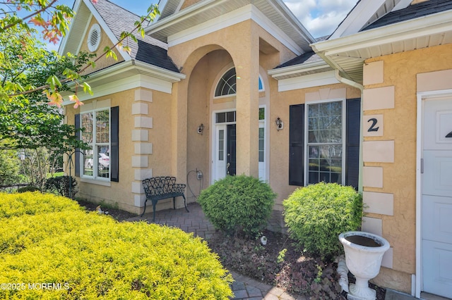 doorway to property with roof with shingles and stucco siding