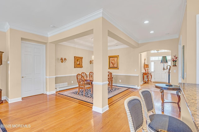 entryway featuring ornamental molding, baseboards, baseboard heating, light wood-type flooring, and a baseboard heating unit