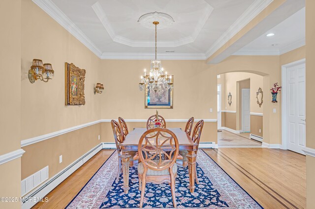 dining area featuring a baseboard radiator, arched walkways, a chandelier, light wood-type flooring, and a tray ceiling