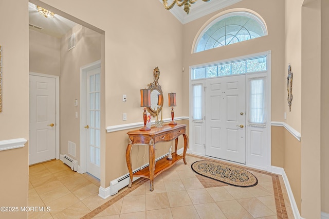 tiled entrance foyer with visible vents, ornamental molding, a towering ceiling, baseboards, and a baseboard radiator