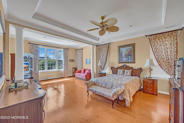 bedroom with a raised ceiling, light wood-type flooring, and ornate columns