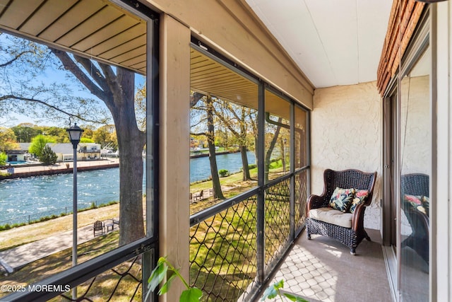 sunroom featuring a water view