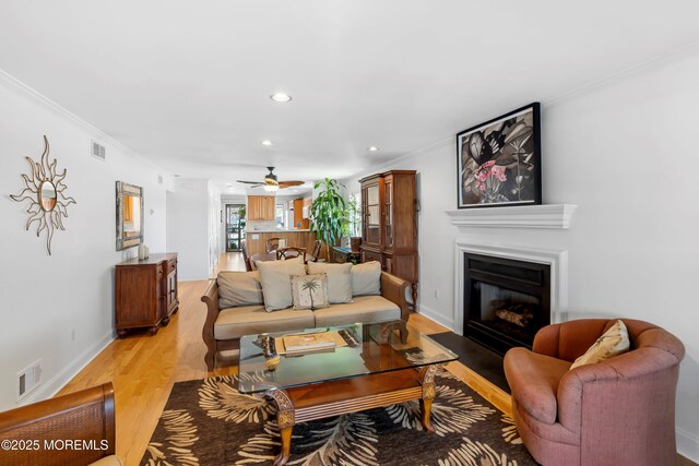living room with visible vents, recessed lighting, light wood-style floors, and a fireplace with flush hearth